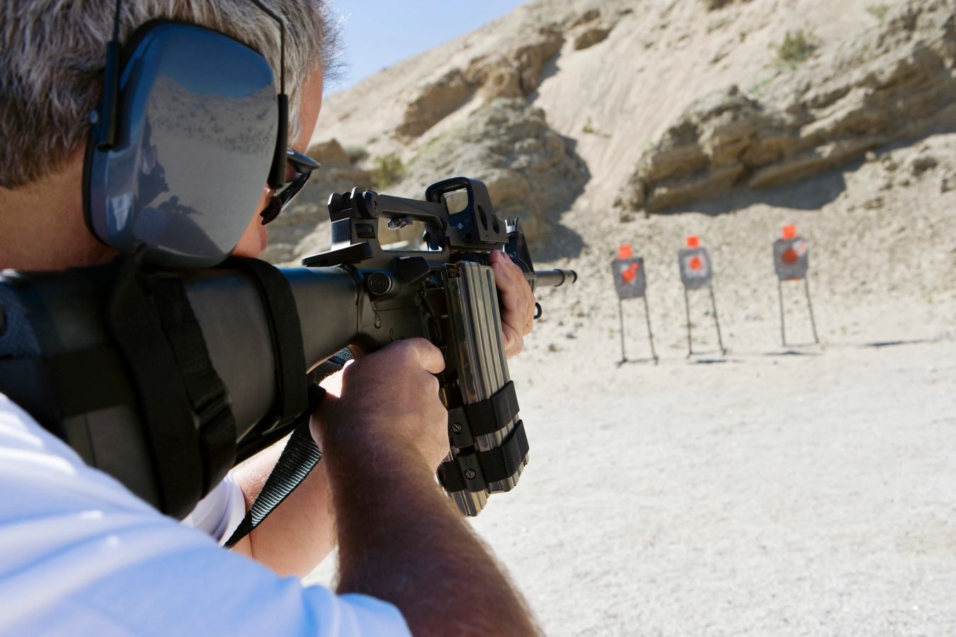 Stock photo, illustrative. Hands hold a pistol resting on a stand at a counter, with other pistols nearby.
