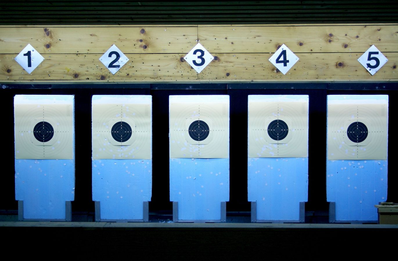 Stock photo, illustrative. Five numbered paper targets hanging at an indoor range.