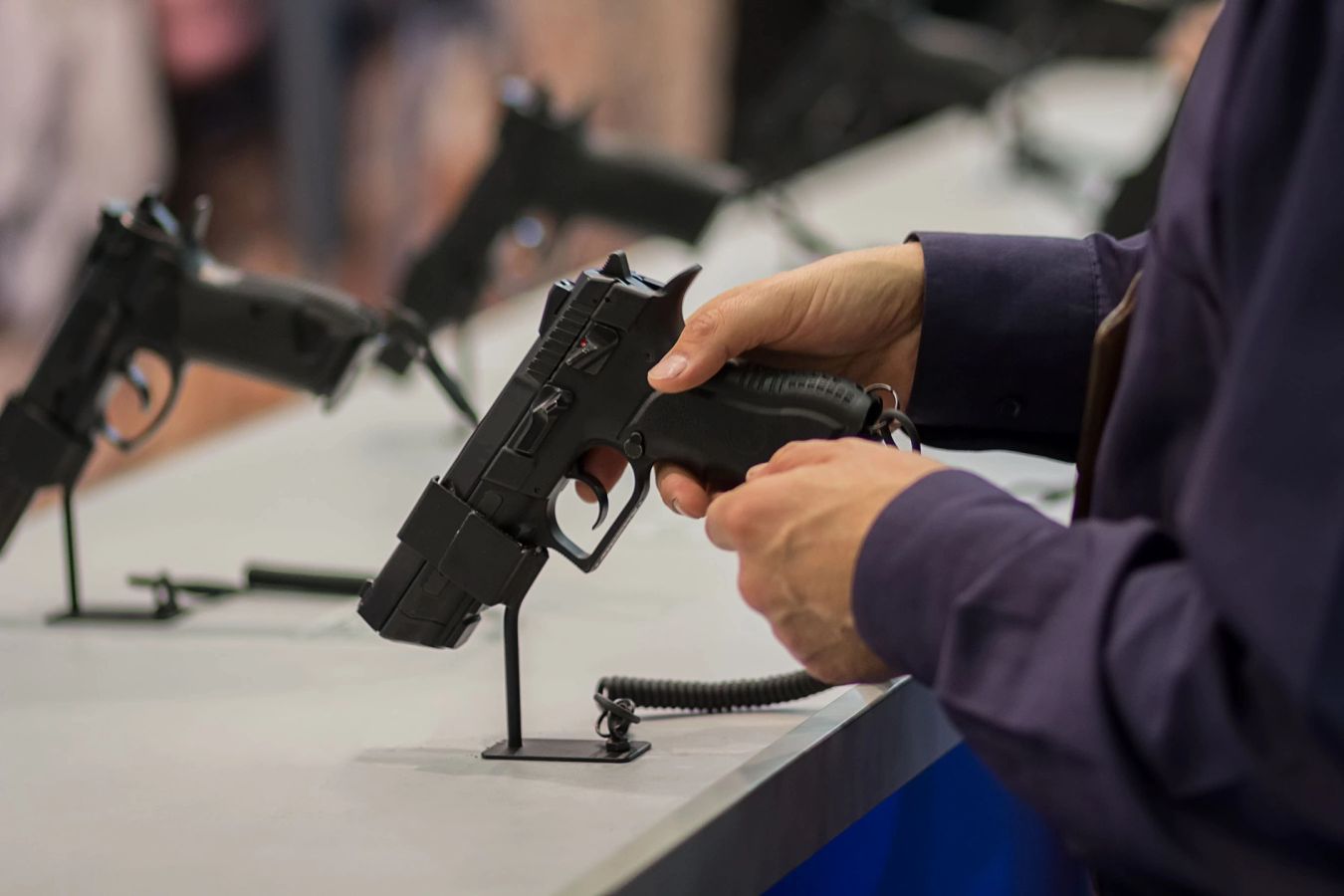 Stock photo, illustrative. A person wearing earmuffs aims a rifle toward paper targets at an outdoor range.